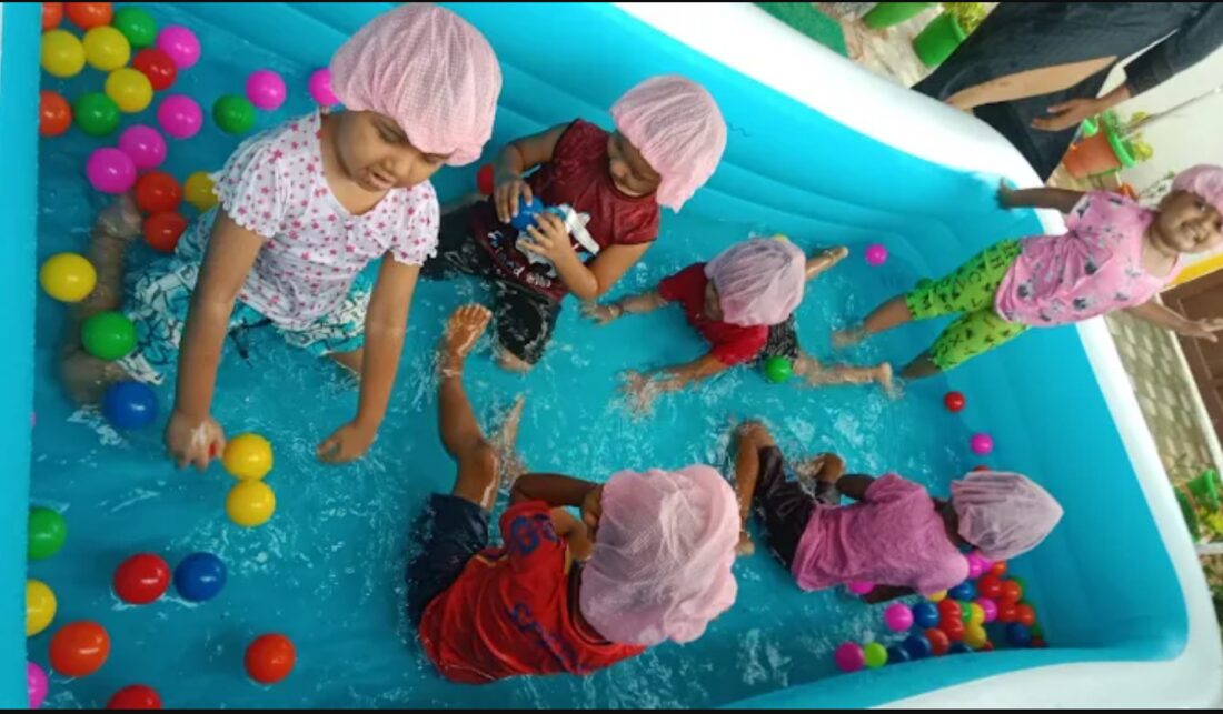 Children playing in a water and ball pool wearing shower caps