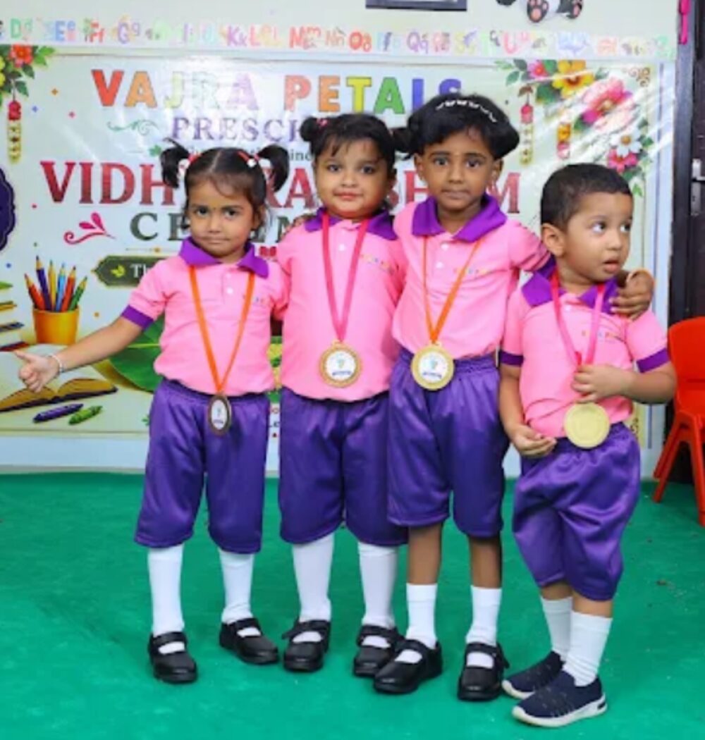 Four children in pink and purple Vajra Petals uniforms wearing medals at the Vidhyarambham ceremony